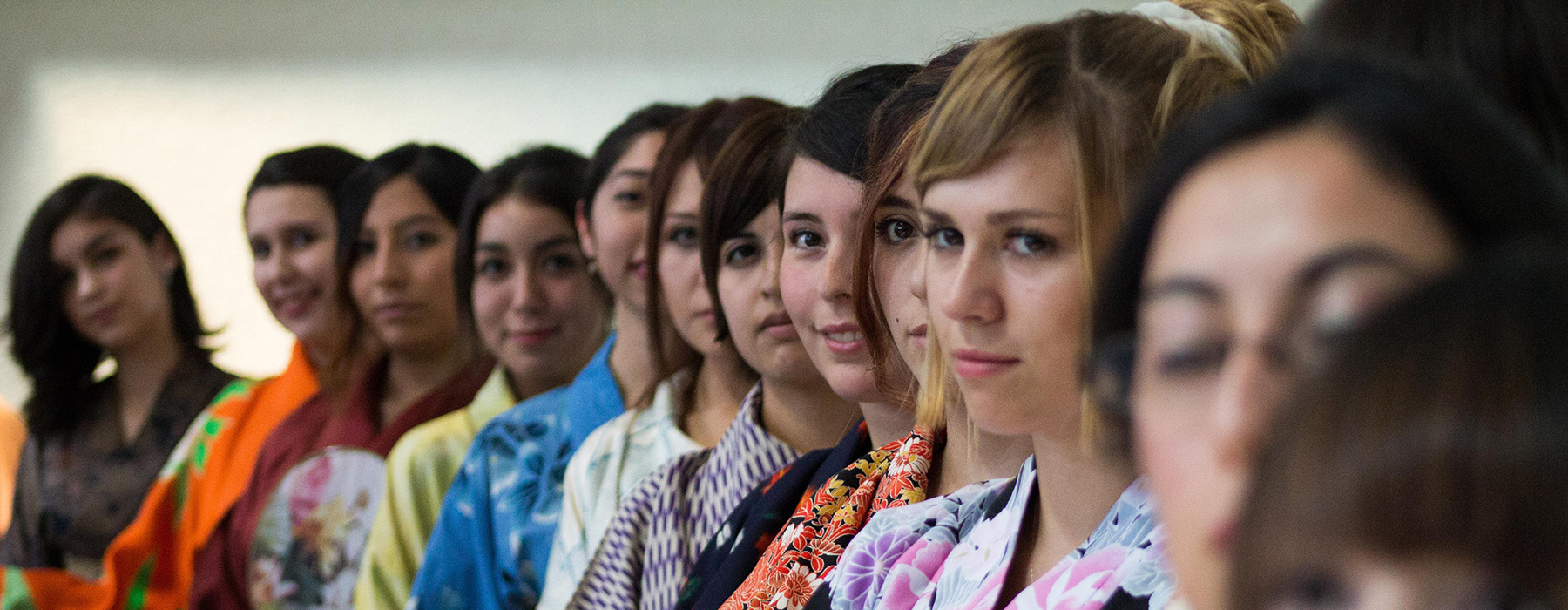 Ragazze europee e asiatiche in fila che indossano kimono colorati