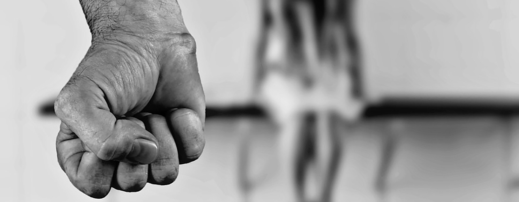 Foto in bianco e nero con un pugno in primo piano e una donna seduta su una panchina