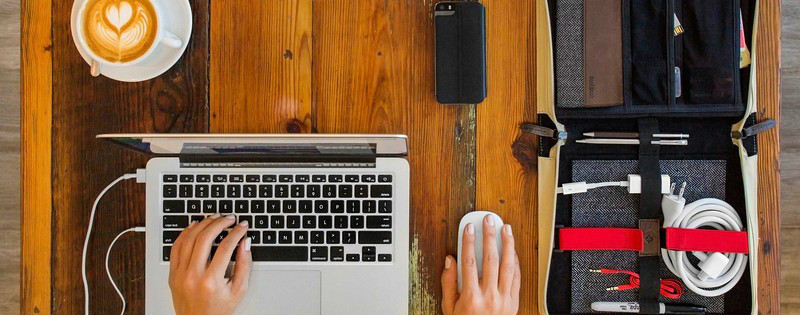 Ragazza che scrive al computer davanti a un cappuccino