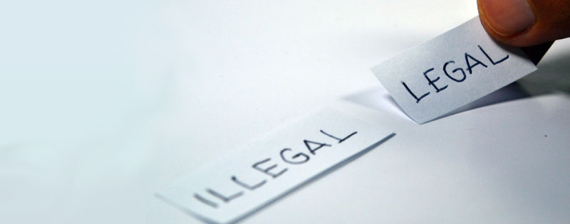 Una mano indica due pezzi di carta con scritto 'Illegal' e 'Legal'