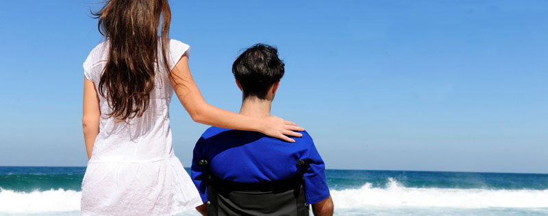 Ragazza e ragazzo in sedia a rotelle guardano il mare all'orizzonte
