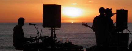 Una band che suona sulla spiaggia al tramonto